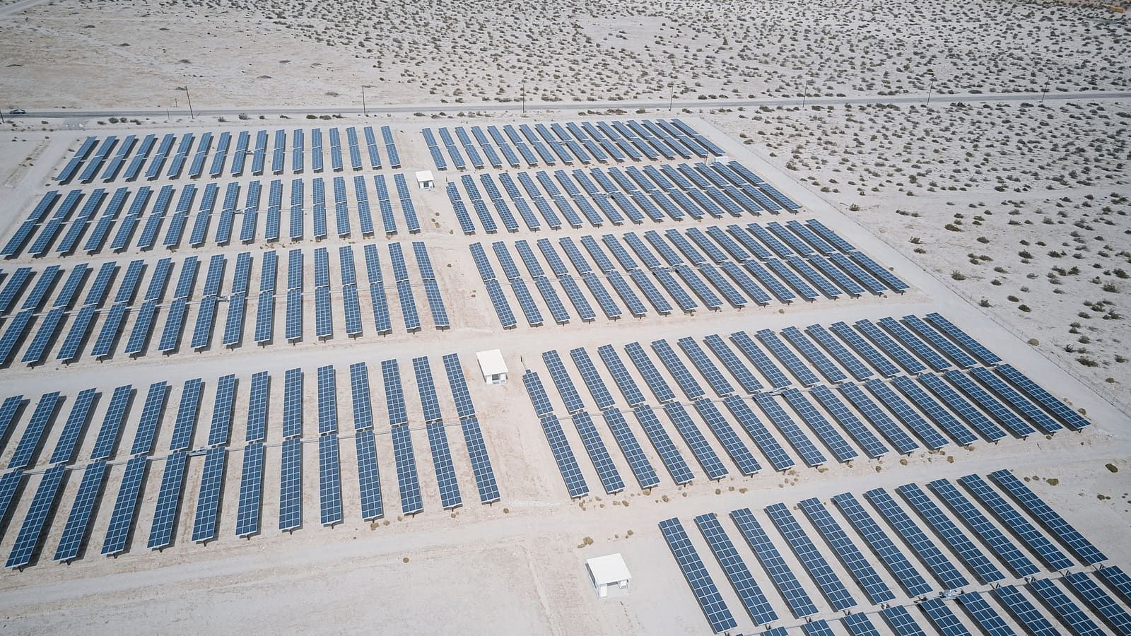Rows of solar panels in open desert under bright sun