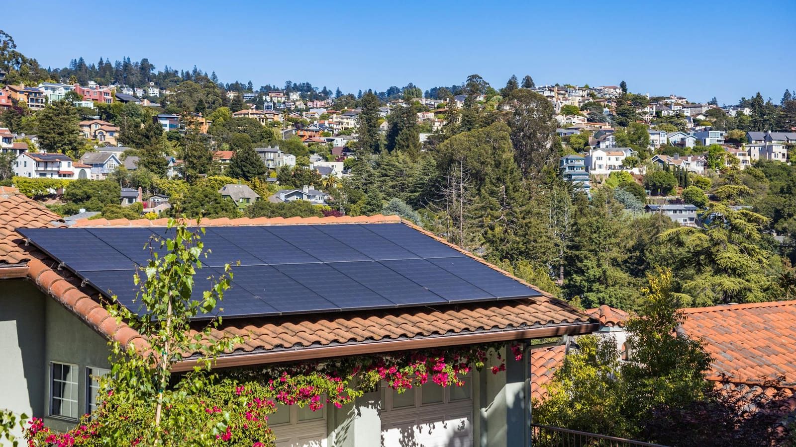 A suburban home with rooftop solar panels under a clear, sunny sky