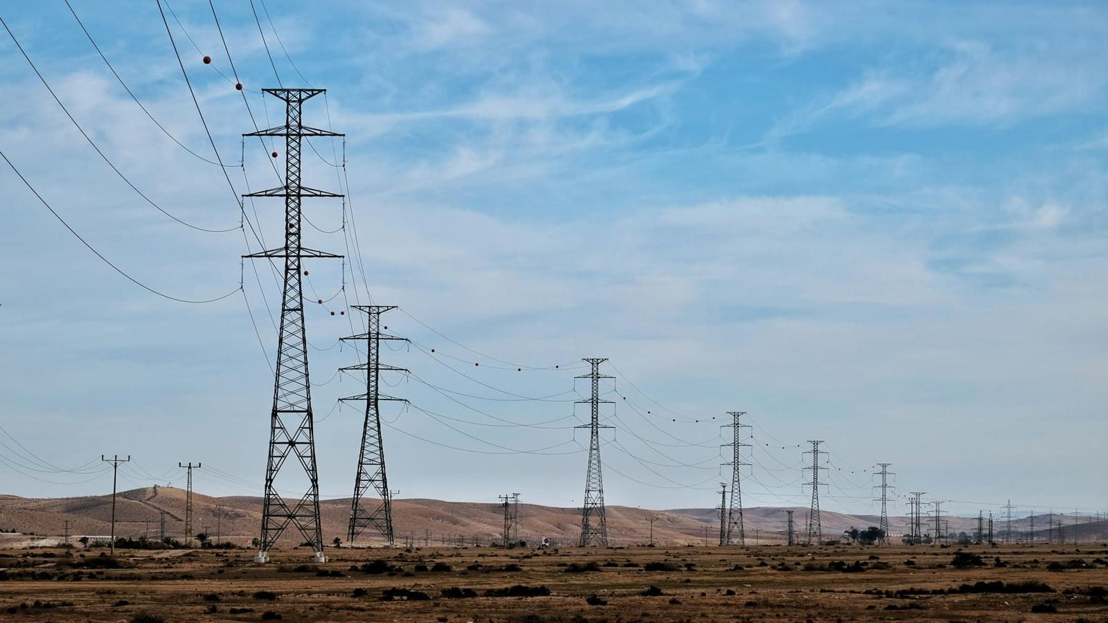 High-voltage transmission towers crossing an open desert landscape