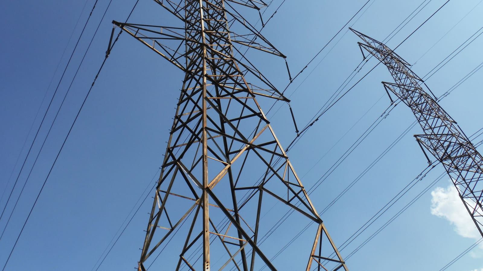 High-voltage electrical transmission towers against a blue sky